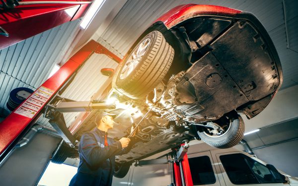Mechanic inspecting suspension system under a lifted vehicle at Pete Nelson Automotive in Sun City, AZ