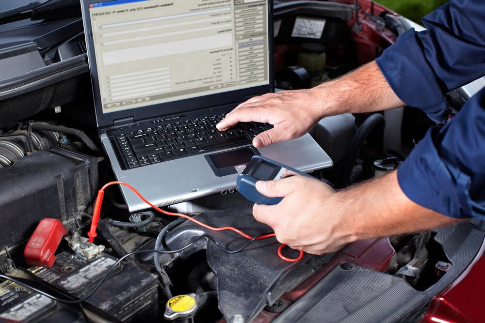 Mechanic performing computer diagnostics on a car engine.